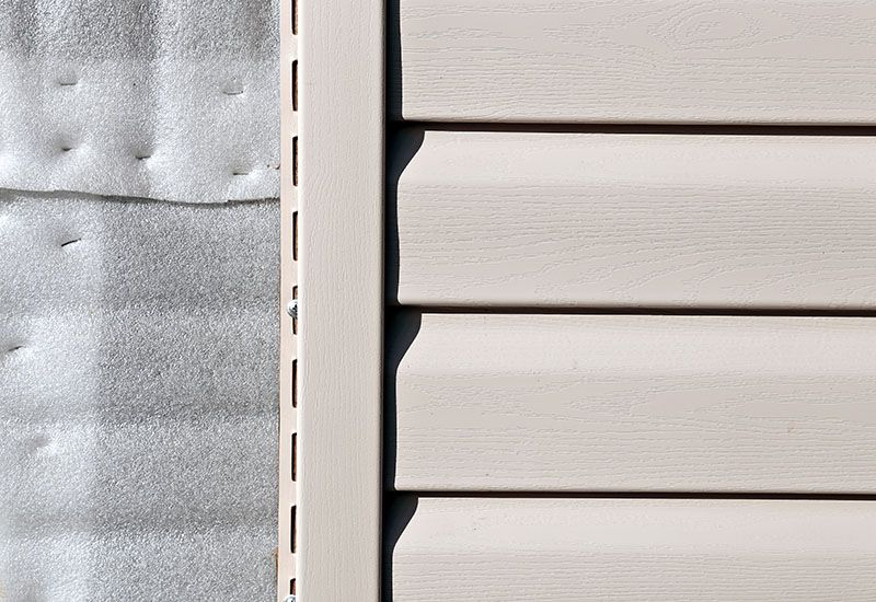 close-up picture of tan vinyl siding showing backing behind siding installation.